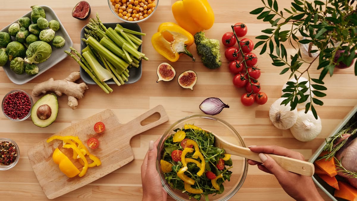 Top view of fresh vegetables and salad preparation on a wooden table, perfect for healthy eating concepts.